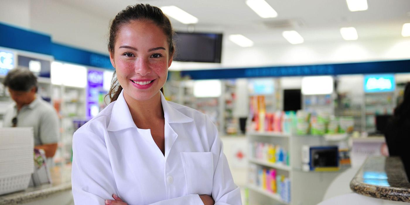 Woman in White coat standing in front of a pharmacy counter